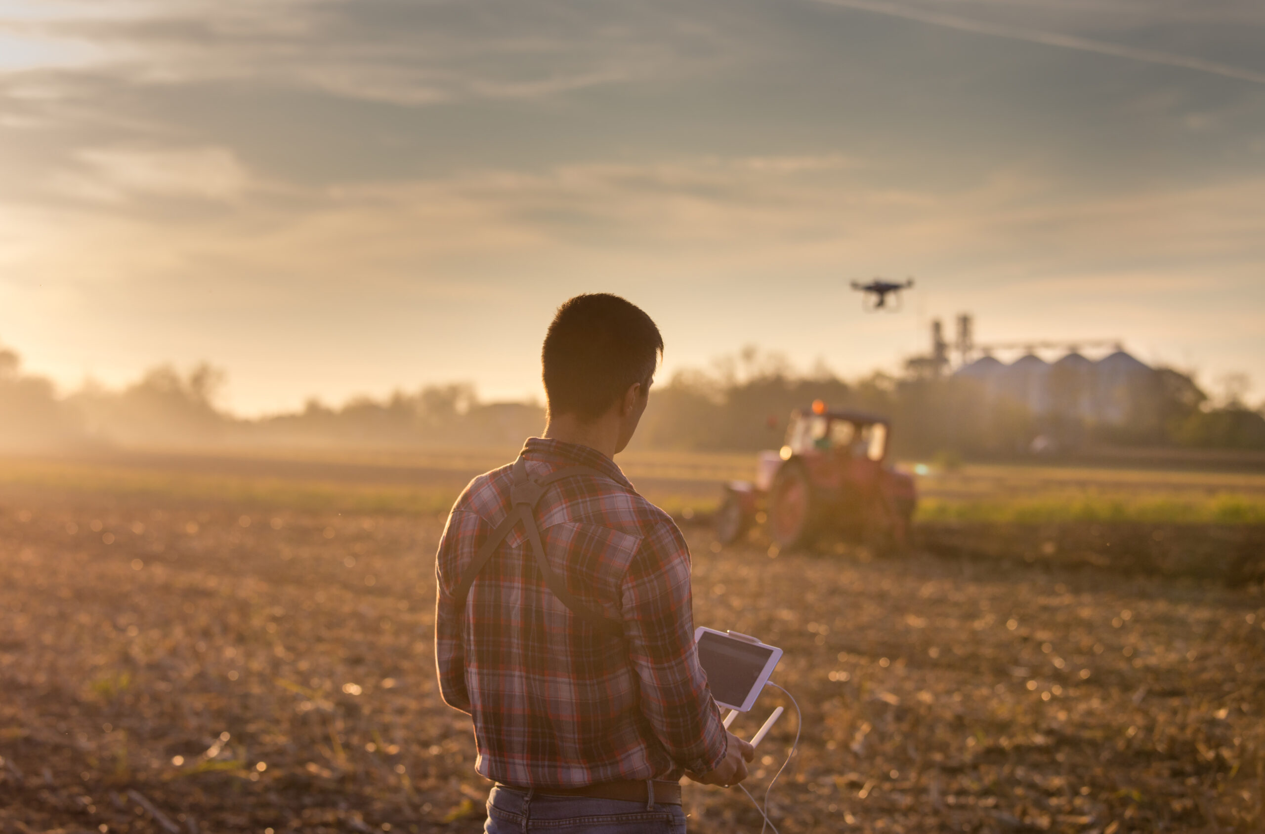 Farmer navigating drone above farmland